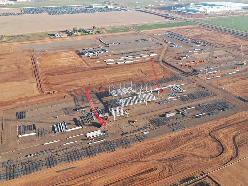 Aerial photo of an automotive manufacturing plant in development. Shows cranes, bulldozers and steel skeleton of building.
